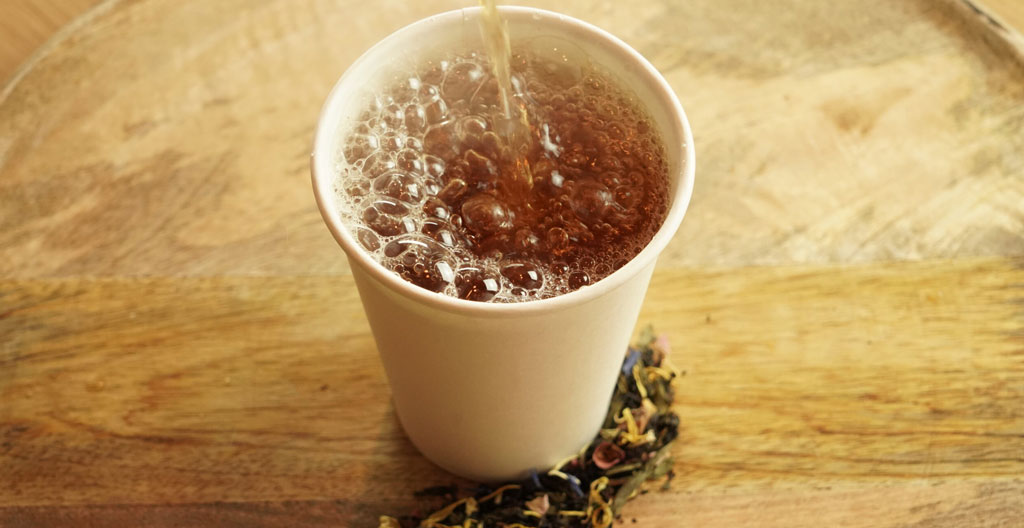 Trois tasses de thé présentant des intensités de couleur différentes allant du vert pâle au brun foncé sur un comptoir en marbre blanc